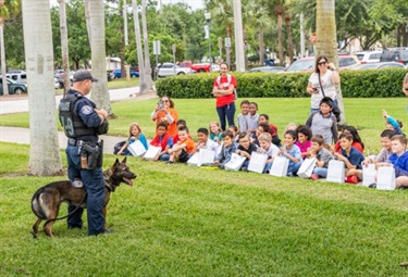 Officer with dog speaking to group of young students