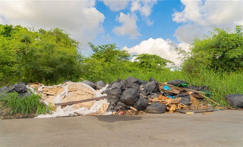 pile of trash and materials and high weeds