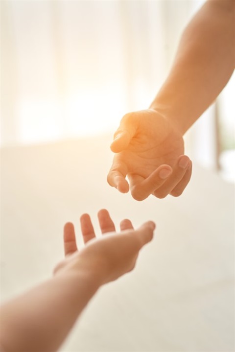 hands extended to each other in sunlight